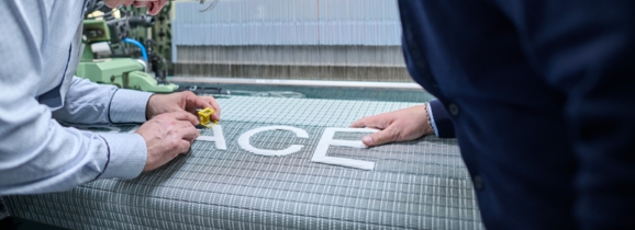 Zwei Personen prüfen das getzspace-Gewebe an der Webmaschine.