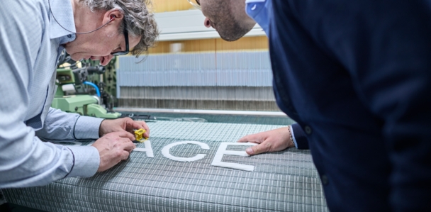 Zwei Personen prüfen das getzspace-Gewebe an der Webmaschine.