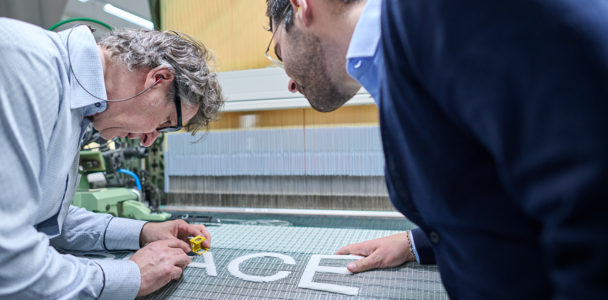Zwei Personen prüfen das getzspace-Gewebe an der Webmaschine.