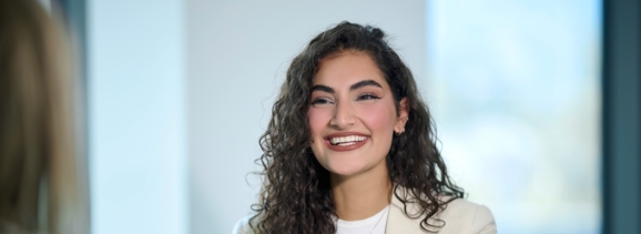 Eda Kurt sits in front of a laptop and smiles at the camera.