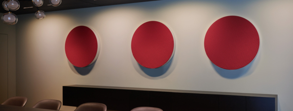 Drei runde Paneele in Weinrot zieren die Wand in einem Besprechungsraum.