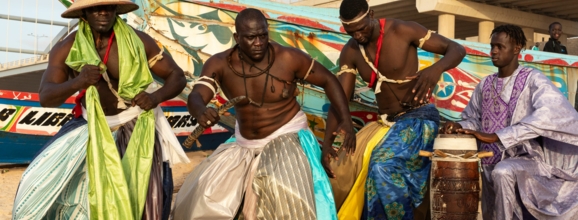 La Lutte-Sportler vor einer bunten Kulisse am Strand von Dakar.