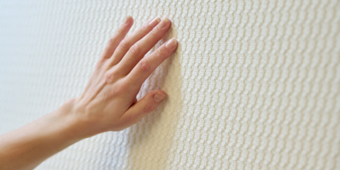 A hand strokes the structure of the acoustic textiles from acunic.