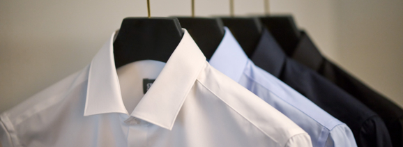 Vier gebügelte Herrenhemden in den Farben Weiß, Hellblau und Schwarz stellen die Modestoffe von Getzner Textil dar.