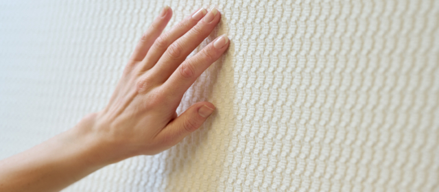 A hand strokes the structure of the acoustic textiles from acunic.